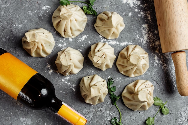 Khinkali, Georgian dumplings, traditional Georgian cuisine. Blue background, a bottle of wine and a rolling pin. copy space.