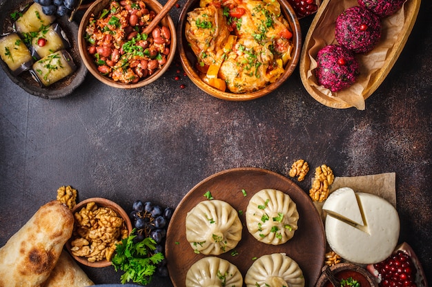 Khinkali, phali, chakhokhbili, lobio, cheese, eggplant rolls, dark table.