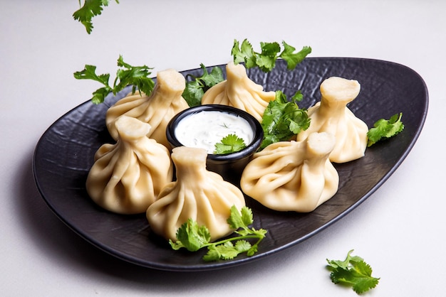 Khinkali with white sauce on a dark plate on a light background