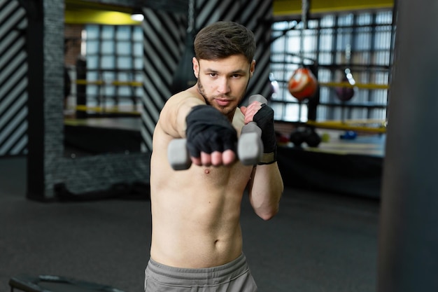 Kickboxer는 체육관에서 덤벨로 원형 운동을합니다.