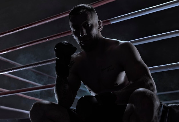 Kickboxer is sitting near the ring and motivatingly shows his fi