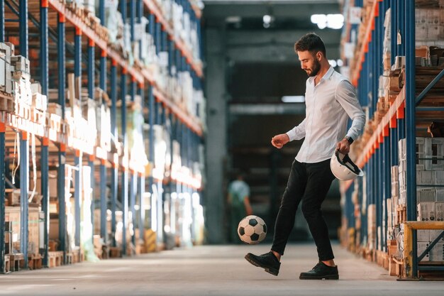 Kicking soccer ball Storage worker is in the warehouse with bunch of products