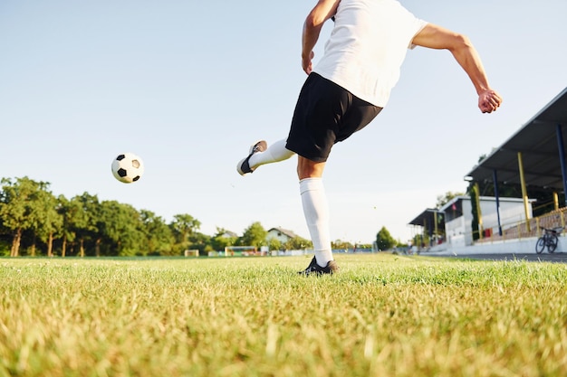 ボールを蹴る若いサッカー選手は、スポーツ分野でトレーニングを受けています