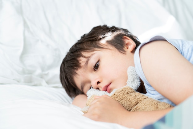 7 살짜리 아이 침대에 누워, 아침 빛으로 자신의 침대 방에서 아침을 깨우는 졸린 아이