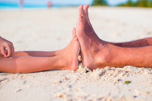 Kid and adult feet on white sandy beach