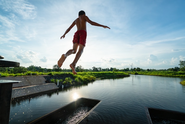 kid in the air while jumping into lake with nice sunray - summer nature scenery