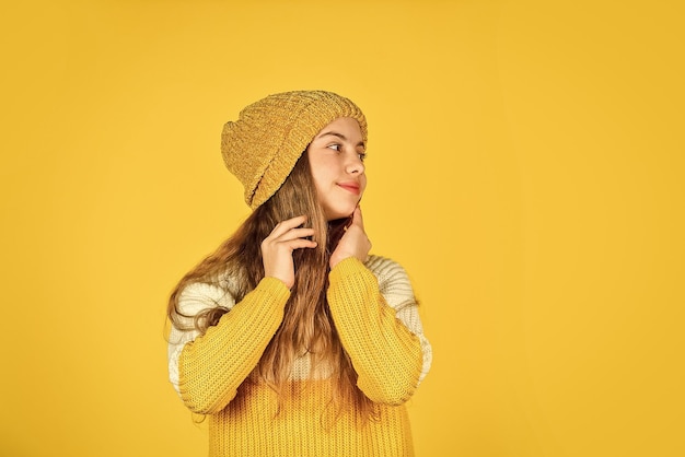 Фото Детская красота и мода согреваются в зимний сезон прогноз холодной погоды счастливый ребенок носит шляпу и любимый свитер детское счастье девочка-подросток желтый фон копия пространства
