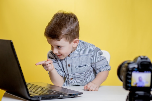 Kid blogger filming video on camera working with the laptop, at home.