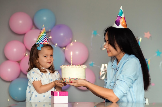 The kid blows out the candles on the cake Mother and daughter are celebrating a birthday