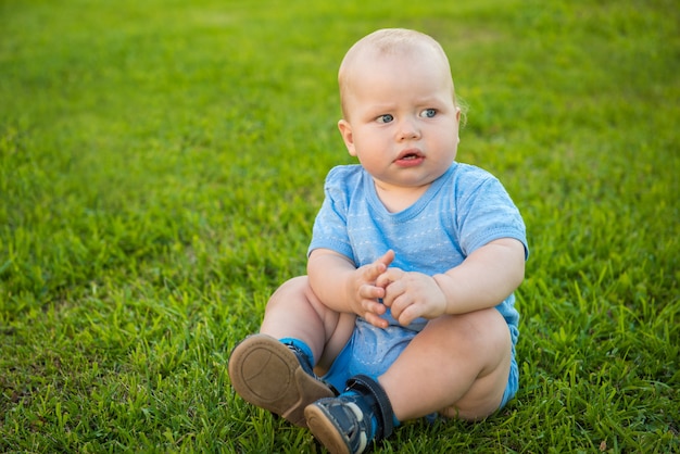 The kid in the blue shirt sitting on green meadow