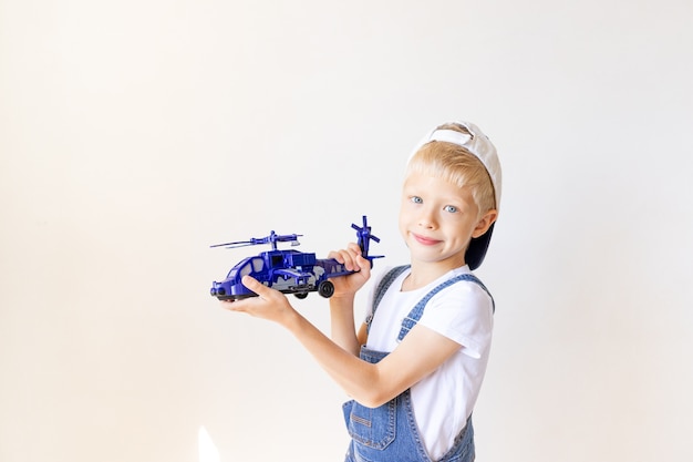 ブルージーンズの子供男の子はヘリコプターのおもちゃで遊んでいます。