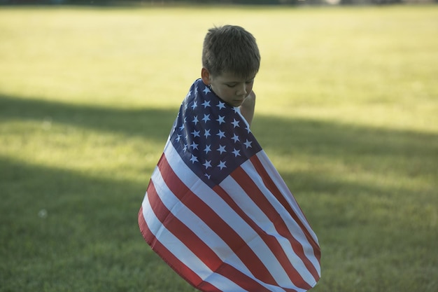 Kid boy celebrating of July 4 Independence Day of USA Child running with american flag symbol of United States over wheat field