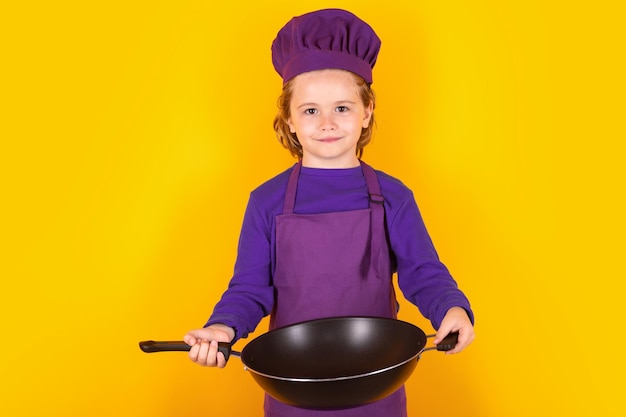 Kid boy chef cook with cooking pan Child in cook uniform Chef kid isolated on yellow background Cute child to be a chef Child dressed as a chef hat