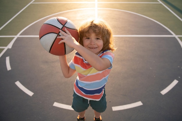 子供の男の子は子供のためのバスケットボールのスポーツをすることに集中しました