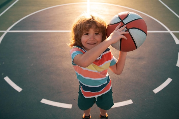 子供の男の子は子供のためのバスケットボールのスポーツをすることに集中しました