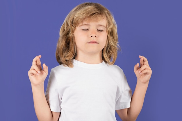 Kid boy crossed fingers isolated studio background child closed eyes with good luck gesture lucky bo