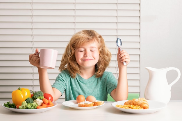 Kid boy eating healthy food vegetables breakfast with milk fruits and vegetables child eating during