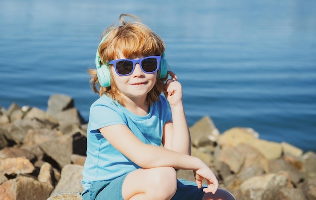 Kid boy in headphones Listening music Child in earphones outdoor