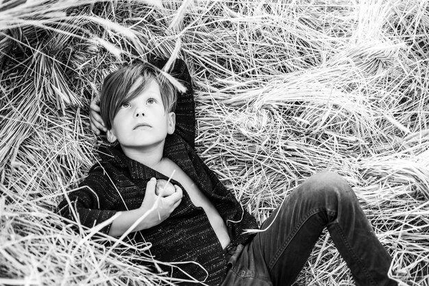 Kid boy holding gold leaf and lies on the hay sale for entire autumn collection incredible discounts