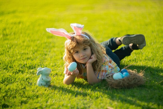 Kid boy hunt egg on easter day outdoor kids easter bunny hunting eggs laying on grass in park wear r...