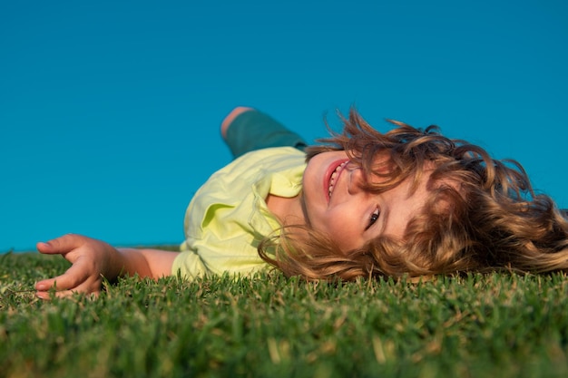 Kid boy laying on the green grass freedom kids and imagination concept summer dream kid dreams on gr