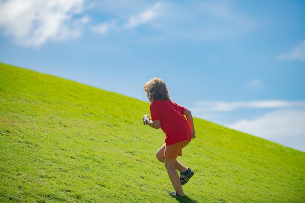 Мальчик играет и бегает в летнем парке