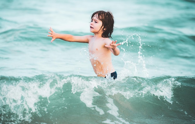 Kid boy playing and swimming in blue sea on summer Blue ocean with wawes Child boy swimming in sea