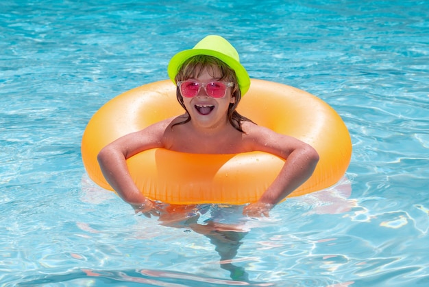 Kid boy playing with inflatable floating ring in swimming pool Summer vacation concept Summer kids portrait in sea water on beach