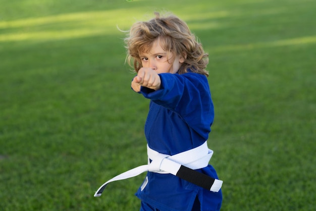 Малыш мальчик практикует карате спорт на открытом воздухе карате дети маленький мальчик в кимоно занимается карате в парке c