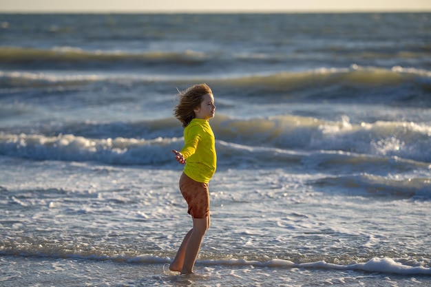 Kid boy running on beach having fun on summer holidays happy kids playing on sea children in nature