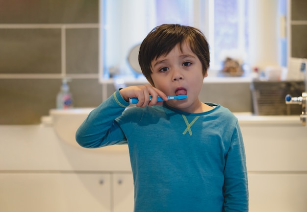 Photo kid brushing teeth and tongue in the bathroom