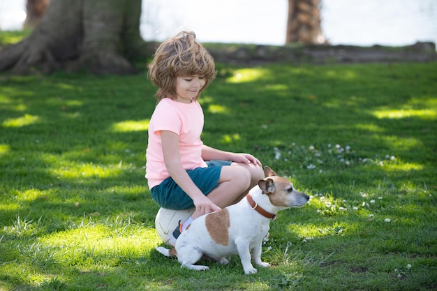 ペットの友達と子犬の子供たちと遊ぶ屋外の子供を歩く犬と一緒に子供を愛撫する犬の子供の少年