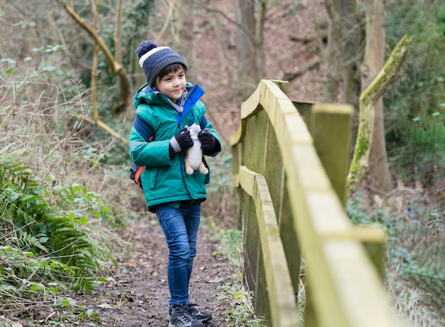 Kid carrying backpack adventure in forest with school trip