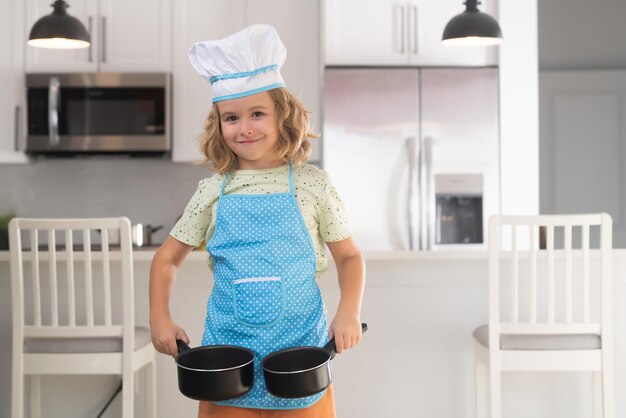 チーフの帽子をかぶって料理をしている子供キッチンでおいしいおいしい料理を作っている子供