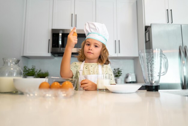 Kid chef cook is learning how to make a cake in the home kitchen Child making tasty delicious Eggs milk and flour ingredients for baking cookies or pancakes