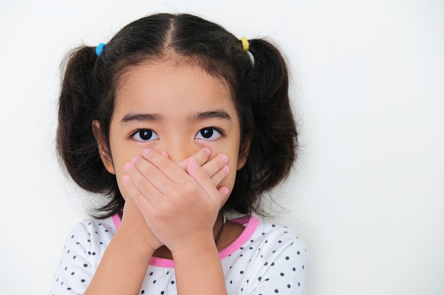 A kid close her mouth with both hands