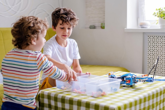 Kid collects robot from plastics details and programmed on tablet robotics