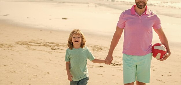 Kid and cropped dad walking on beach in summer vacation holding ball family