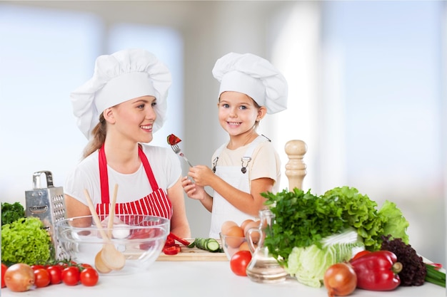 kid daughter feeding mother vegetables in kitchen