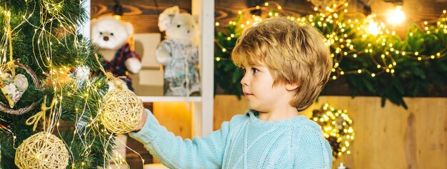 Kid decorating christmas tree child hold bauble over christmas interior background and decorating ch