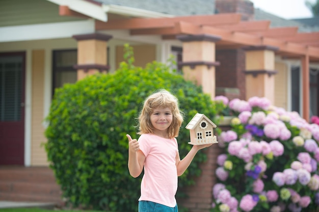 Kid dreaming of new home happy boy holding dream house show thumbs up home insurance concept mortgag