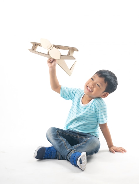 Kid dreams as pilot sitting and holding airplane paper isolated on white 