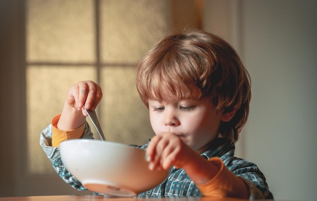 台所で朝食をとっている男の子を食べる子供かわいい子供が家で朝食を食べる赤ちゃんを食べる