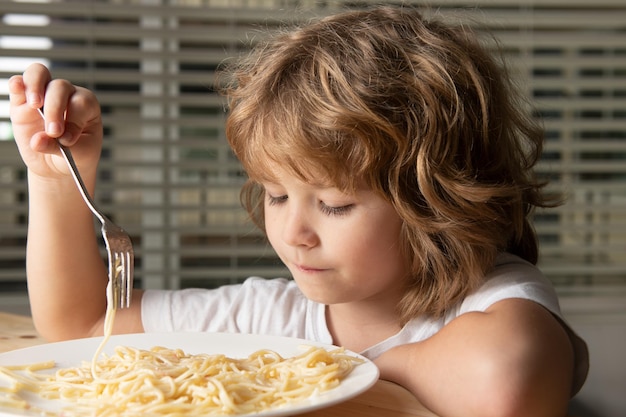 Photo kid eating pasta, spaghetti, portrait, close up head of cute child.