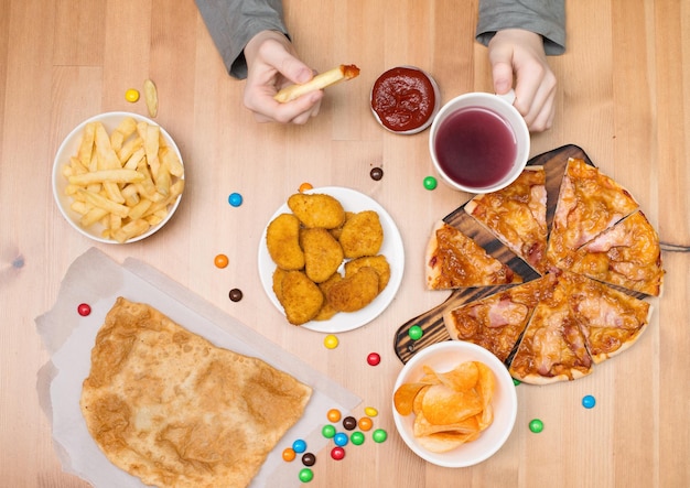 Kid eating pizza nuggets chips and other fast food Fast food junk food concept