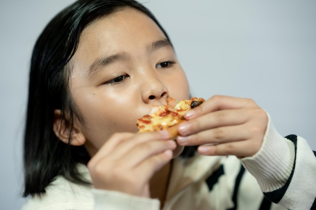 Bambino che mangia pizza su sfondo bianco