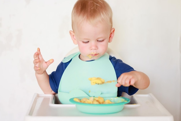 kid eats with a spoon and learns by himself