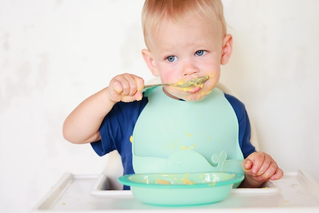 kid eats with a spoon and learns by himself