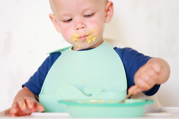 Il bambino mangia con un cucchiaio e impara da solo