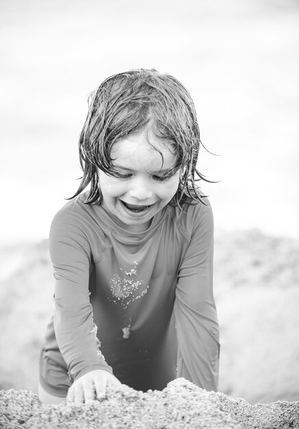 Kid enjoying time at the sand beach Child making sandcastle on sea